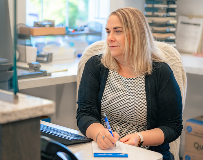 Umbreit, Wileczek & Associates employee sitting at a desk as she writes on a notepad