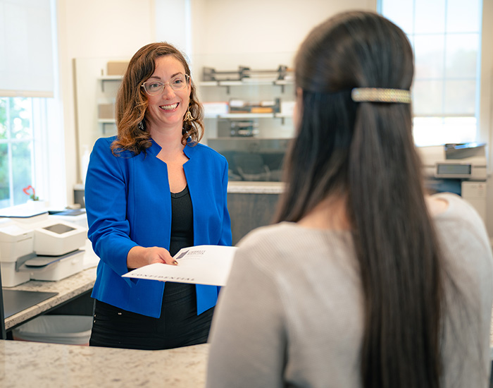 Umbreit, Wileczek & Associates employee standing behind desk and handing over files
