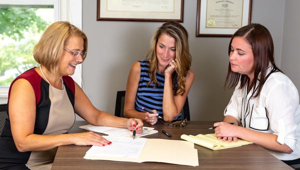Three women meeting to review files that are spread over the table
